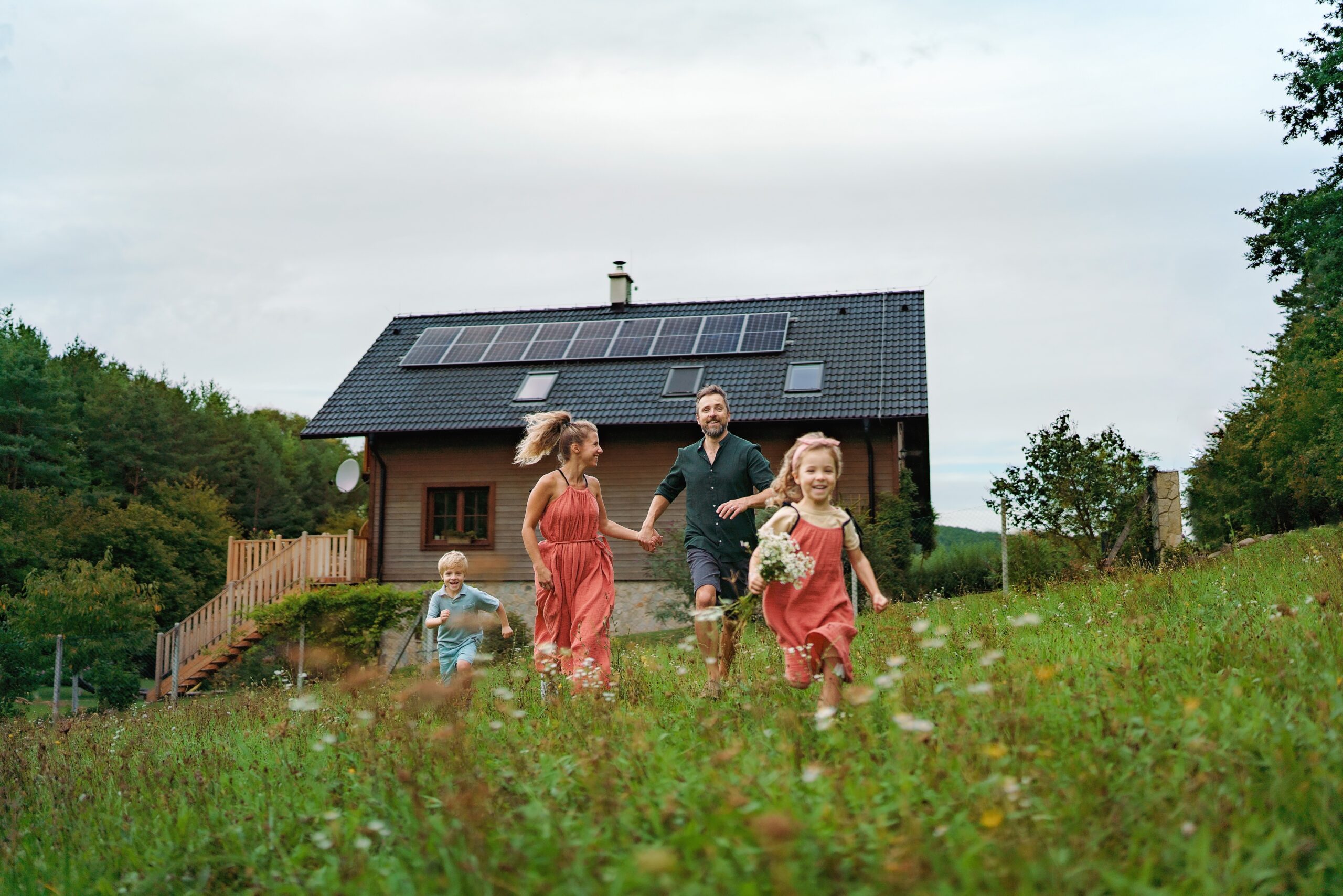 Happy,Family,Running,Near,Their,House,With,Solar,Panels.,Alternative